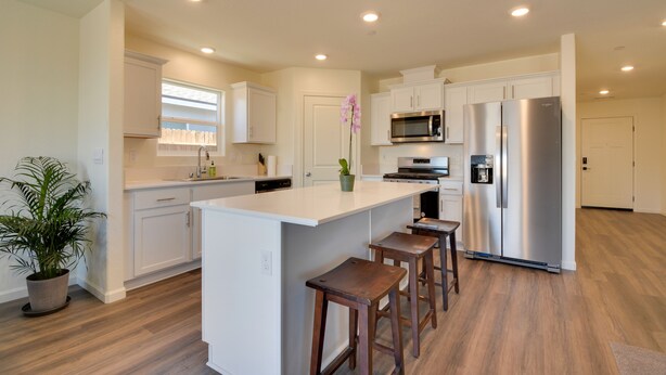 A modern kitchen with white cabinetry, a central island with stools, stainless steel appliances, and a potted plant. - Pet-friendly Merced Vacation Rental! (Merced)