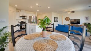 A modern kitchen with white cabinets, a microwave, and a refrigerator. There is a dining area with a round table and woven placemats. A large plant is in the center of the table. - Pet-friendly Merced Vacation Rental! (Merced)