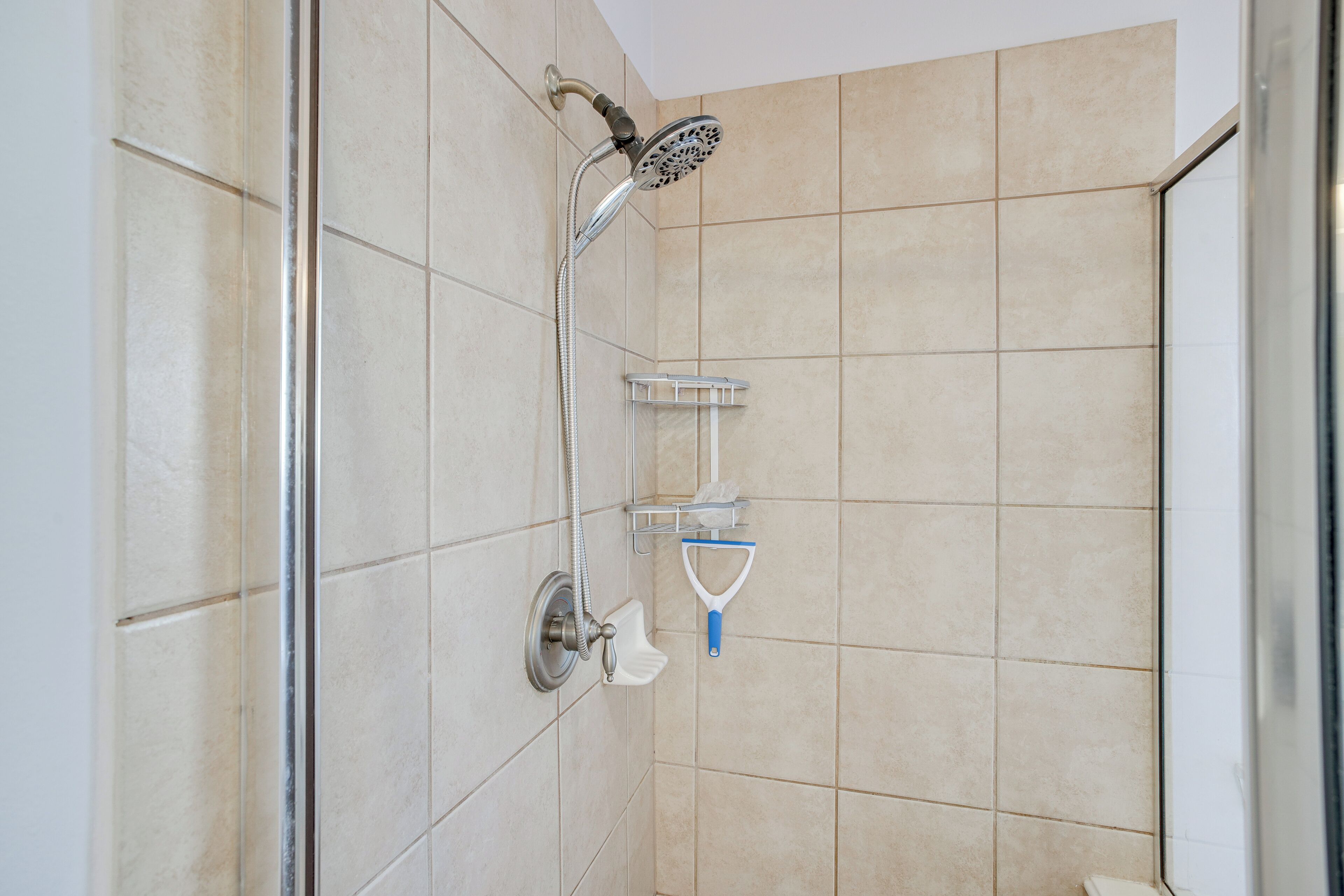 Ducha con cabezal de ducha de mano, grifo empotrado y jabonera.