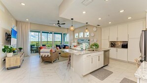 A spacious kitchen with a large island, white cabinetry, and a view to the outdoors. - Serenity on the Sound, steps to pool/grills (Bradenton)