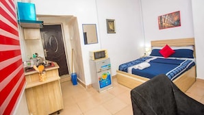 Habitació d'hotel amb un llit, escriptori amb un ordinador, microones i una cuineta petita.