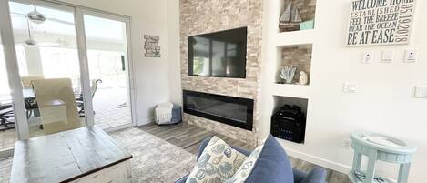 A modern living room with a stone accent wall, a flat-screen TV, and a blue sofa.