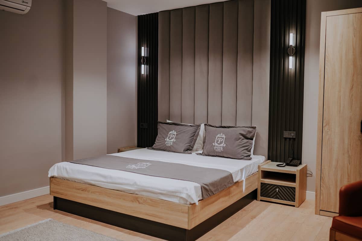 A modern bedroom with a wooden bed, a nightstand, a wardrobe, and a red chair.