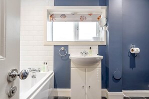 Ein Badezimmer mit Waschbecken, Spiegel und Badewanne.