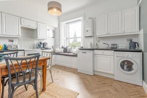 Une cuisine moderne avec des meubles blancs, un lave-vaisselle intégré et un lave-linge.