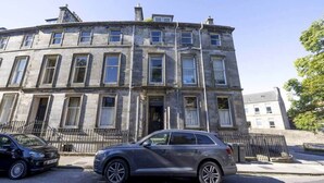 Un immeuble à étages doté d’un style architectural classique, caractérisé par une façade symétrique avec des fenêtres régulièrement espacées et une entrée centrale.