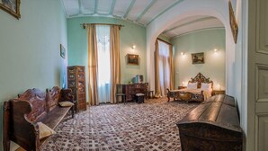 Une pièce avec un tapis à motifs, un banc en bois, un lit doté d’une tête de lit décorée et une commode en bois.