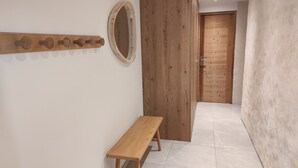 A hallway with a wooden bench, a wooden door, and a wall-mounted mirror. - Ferme Ancienne 1876 Rénovée, Appartement Neuf Tout Confort 8 Personnes (Le Grand-Bornand)