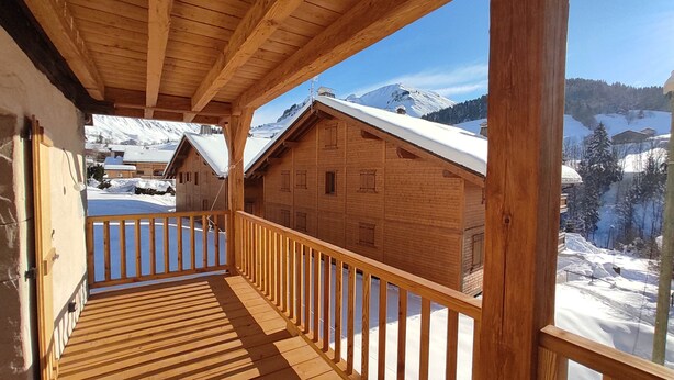 A wooden cabin with a balcony overlooking a snowy mountain landscape. - Ferme Ancienne 1876 Rénovée, Appartement Neuf Tout Confort 8 Personnes (Le Grand-Bornand)