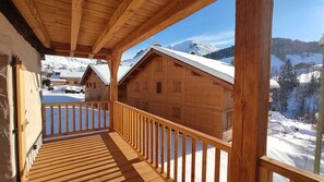 Une cabane en bois dotée d’un balcon donnant sur un paysage montagneux enneigé.