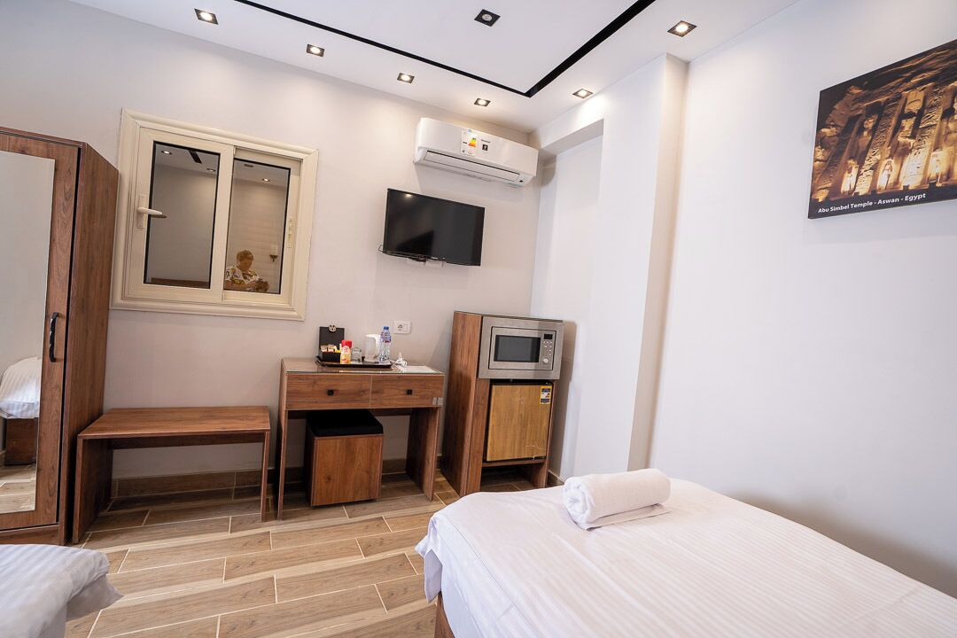 Habitación de hotel con cama, escritorio, computadora, televisor y aire acondicionado.