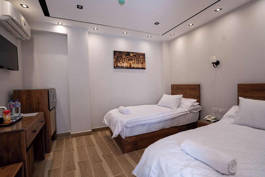 Ett hotellrum med två sängar, ett skrivbord med en tv och en tavla på väggen.