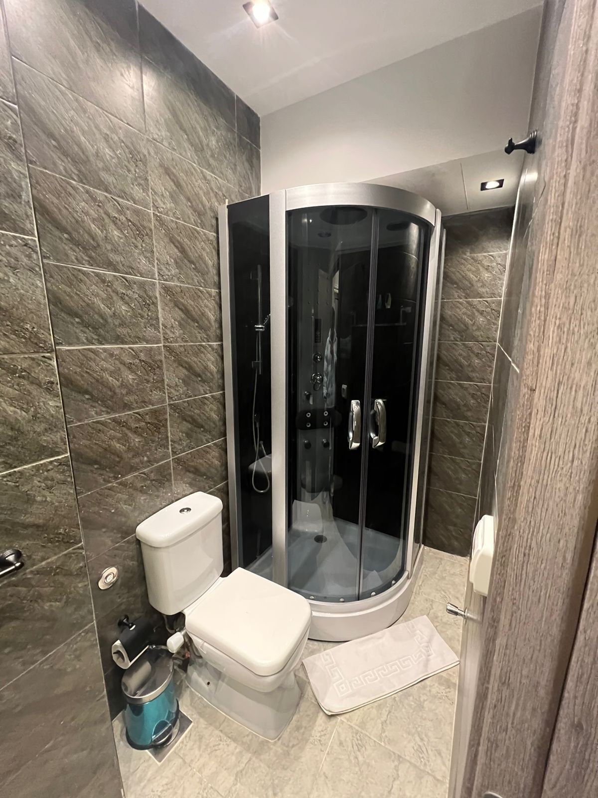 A modern bathroom with a glass-enclosed shower, a toilet, and a bidet.