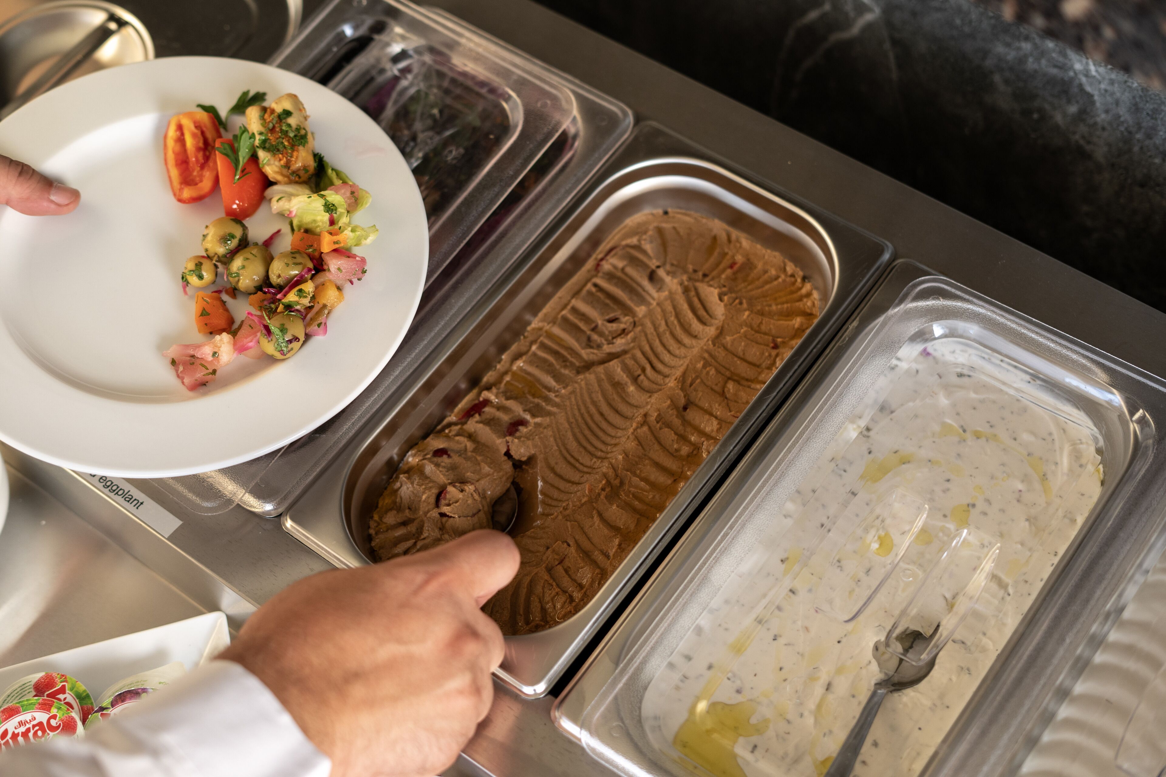 A buffet with various food options including a salad, chocolate ice cream, and a creamy dessert.