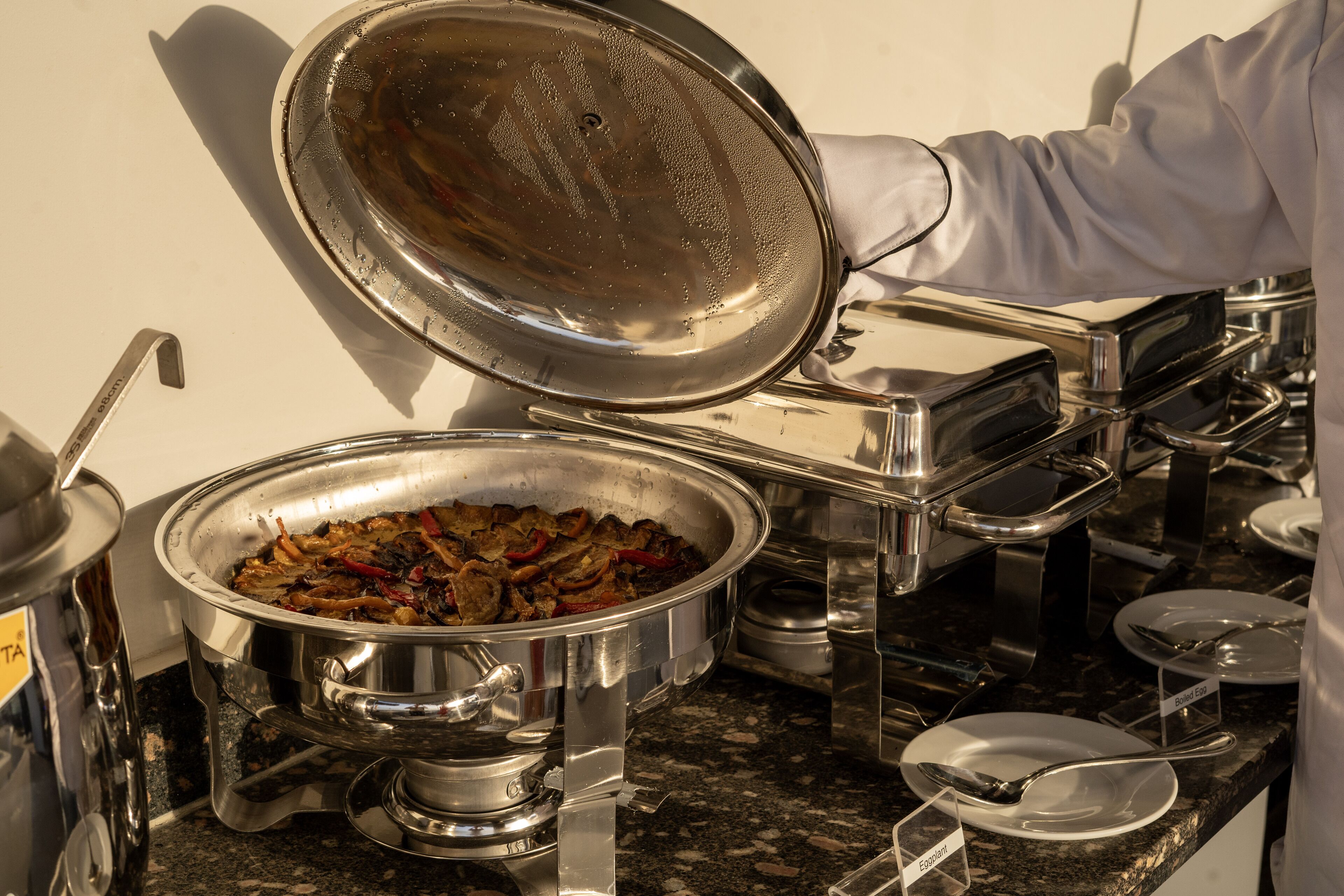A buffet setup with various food containers and utensils.