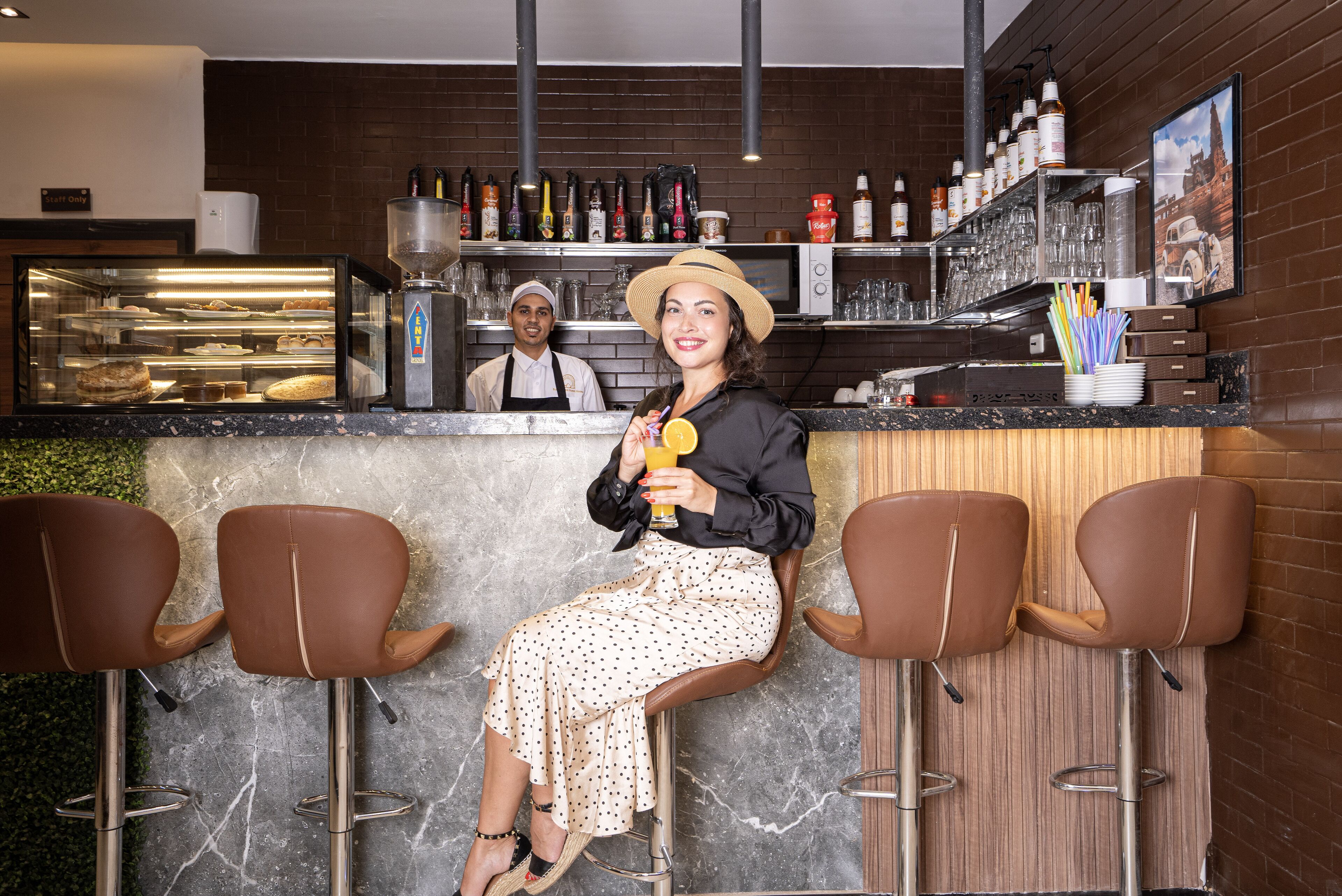 A bar area with stools, a counter, and a display case with baked goods.