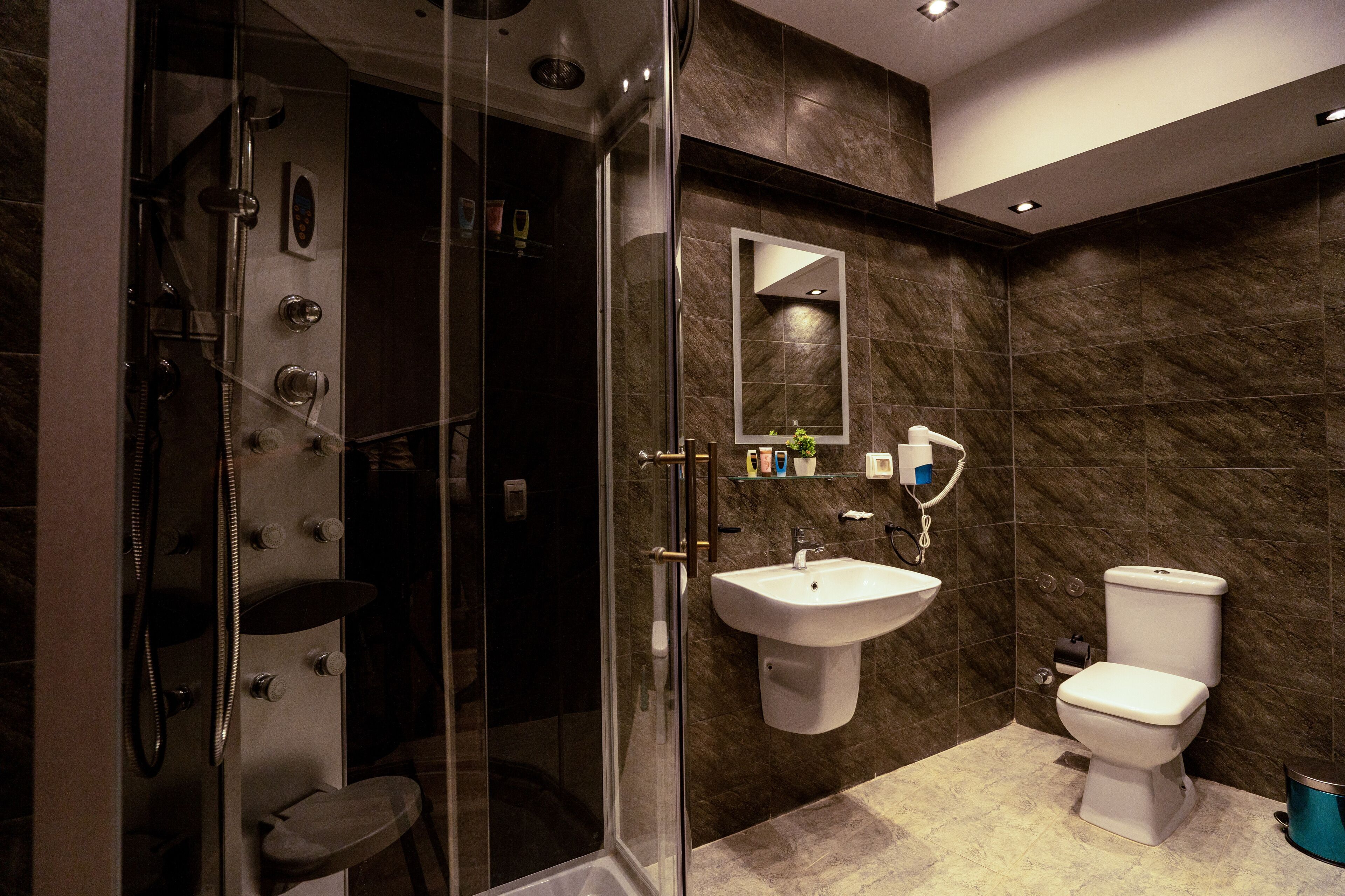 A modern bathroom with a glass-enclosed shower, a white sink, and a toilet.