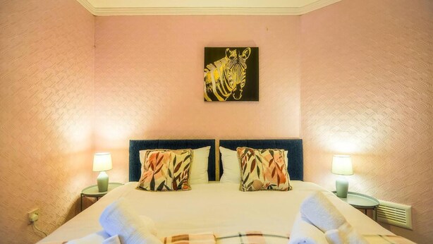 A hotel room with a bed, two pillows, two bedside tables with lamps, and a painting on the wall. - 3BR 6beds Garden Free Parking Wifi Near City Centr (Coventry)