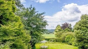 Un exuberante jardín con una mesa y sillas, rodeado de abundante vegetación y árboles.