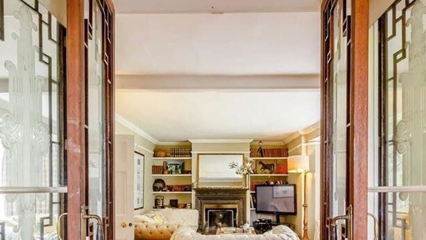 Un salón amplio con chimenea, un sofá blanco grande y una televisión.