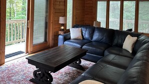 Interno di una baita di legno con un divano componibile, un tavolino da caffè e una ventola a soffitto.