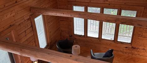 A wooden cabin interior with a black leather sofa, a small table, and a ceiling fan.