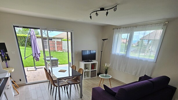 En kompakt opholdsstue med sofa, spisebord, stole, et fjernsyn og en vaskemaskine.