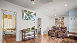 Un vaste espace de vie doté d’un plancher en bois, d’un canapé en cuir marron, d’une table basse en bois et d’un cadre photo fixé au mur.