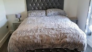 A bedroom with a tufted headboard, a large fluffy rug, and a painting on the wall. - Charming 2 Bed Cottage in Nidderdale Near Harrogat (Harrogate)