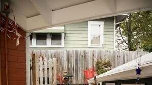 A wooden staircase leading to a porch with a rustic design, a wooden fence, and a small birdhouse with a star decoration.