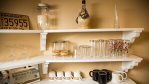 A shelf with various glassware, including wine glasses, mason jars, and decorative pitchers.