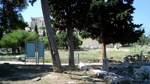 An outdoor area with trees, a stone wall, and a signboard. - 3-Generations Athenian home at the foot of the Acropolis hill in Athen"s center (Athina)