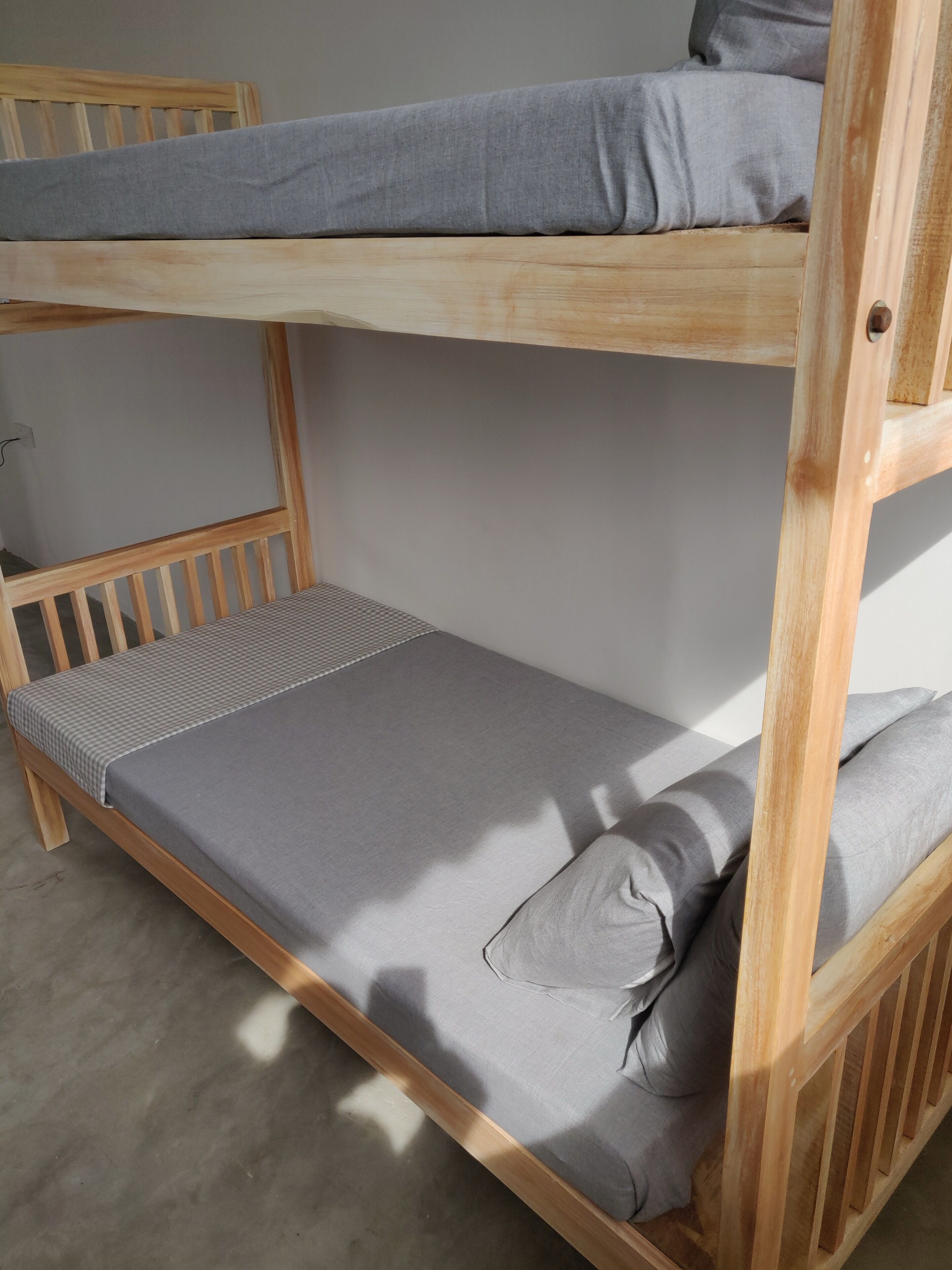 Una cama individual con ropa de cama gris y una manta a cuadros.