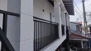 A white building with a black balcony railing and a red-tiled roof. - Dipndoze (Ahangama)