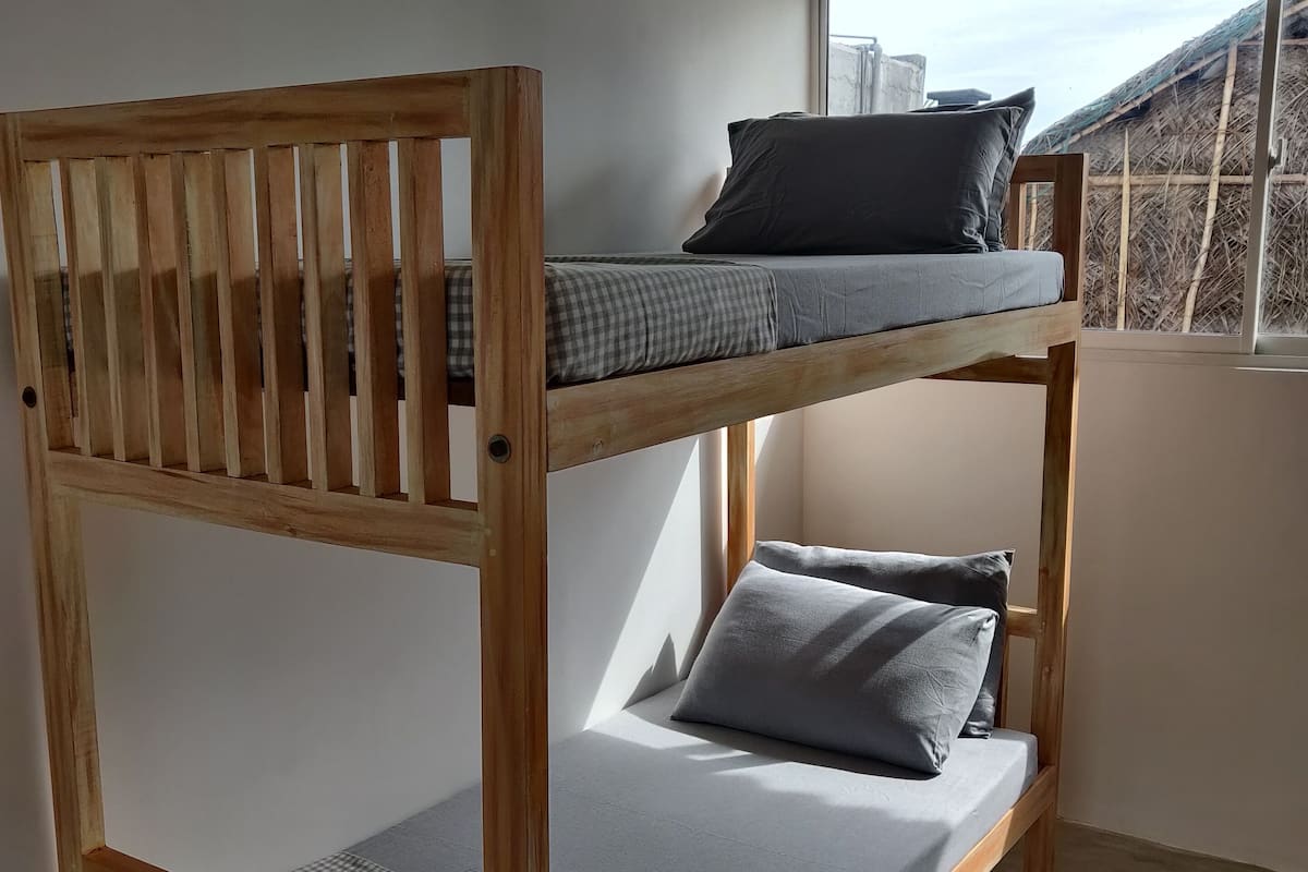 A bunk bed with grey bedding and a checkered blanket.