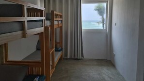 A room with bunk beds, a window with curtains, and a view of the sea. - Dipndoze (Ahangama)