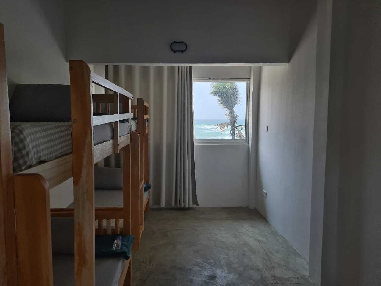 A room with a bunk bed, a window with curtains, and a view of the sea.