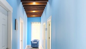 A hallway with wooden beams, blue walls, and a patterned floor. - 3bd 2 bth House. POOL! HOTTUB! Breathtaking Ocean Views! 2-min drive to beach! (Santos Guardiola)