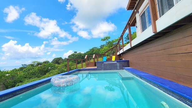 A swimming pool with a clear view of the ocean and lush greenery in the background. - 3bd 2 bth House. POOL! HOTTUB! Breathtaking Ocean Views! 2-min drive to beach! (Santos Guardiola)