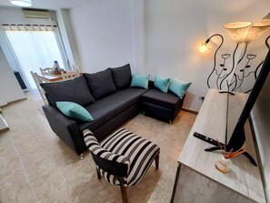 A living room with a sectional sofa, a striped armchair, a wooden coffee table, and a floor lamp. - Cómodo departamento céntrico con estilo y personalidad (Bahía Blanca)