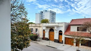 Vista de la calle con un edificio que presenta puertas de madera arqueadas y un tejado de tejas rojas.