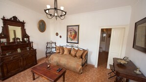 A room with a sofa, a wooden table, a mirror, a chandelier, and a painting on the wall. - Galiello & Bacco by CorfuEscapes (Corfu)
