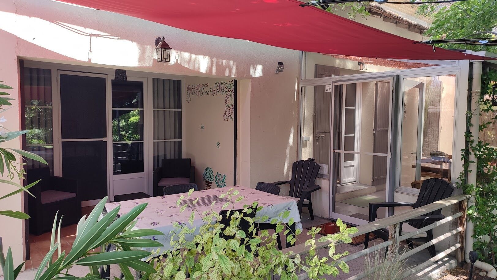Un espacio de patio cubierto con una mesa, sillas y plantas en macetas, además de una puerta corrediza de vidrio.