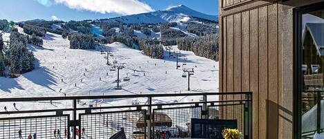 A balcony with a view of a ski slope and a mountain.