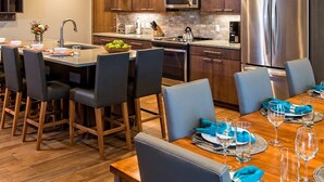 Una cocina moderna con armarios de madera oscura, electrodomésticos de acero inoxidable y una isla central con taburetes de bar.