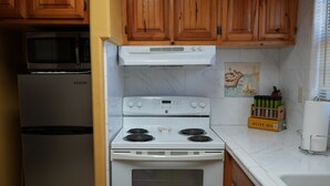 A kitchen with wooden cabinets, a microwave, a refrigerator, a stove, and a sink. - Sunshine cabin with a Shared fishing pier Not waterfront (Rio Hondo)