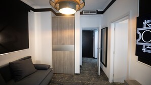 A modern hallway with a dark patterned floor, a sofa with cushions, a wooden wardrobe, and a ceiling light fixture. - Opera Hotel  (Timisoara)