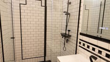 A modern bathroom with white subway tiles, a glass-enclosed shower, a black-framed mirror, and a white sink.