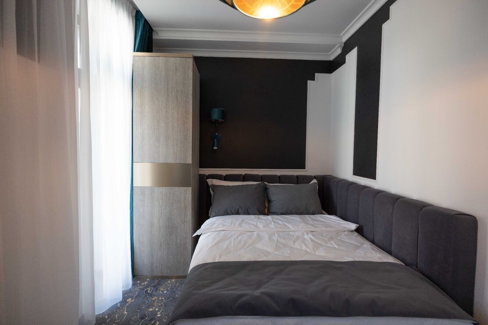 Una habitación de hotel moderna con una cama grande, un armario y una pared decorativa oscura.