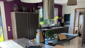 Een moderne keuken met een groot schiereiland, donkere kastjes en een raam met uitzicht op groen.